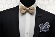 A mannequin is shown wearing a black suit wit our kahki & blue dotted silk knitted bow tie, navy patterned bow tie and matching navy floral lapel pin.