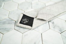 The DM hexagonal logo is shown stitched on the back of the creme men's linen skinny tie by Dear Martian.