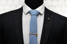 Featured on a mannequin lies the Dear Martian, Aqua Blue Chambray tie with mens acessories; our Kloven gold axe Tie Clip and Vie gold Skull Lapel Pin