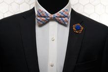 An image of a dandy mannequin dressed in a Dear Martian wooden lapel pin a summer plaid bow tie.