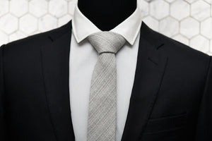 The Barclays Dear Martian neck tie is knotted and displayed on a mannequin wearing a black suit jacket and white button down.