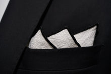 A men's white linen pocket square from Dear Martian, Brooklyn is displayed, folded, in a black jacket.