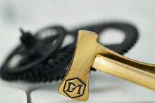A detailed image of the back of the antique brass axe tie bar, which features a hexagon DM logo etching.