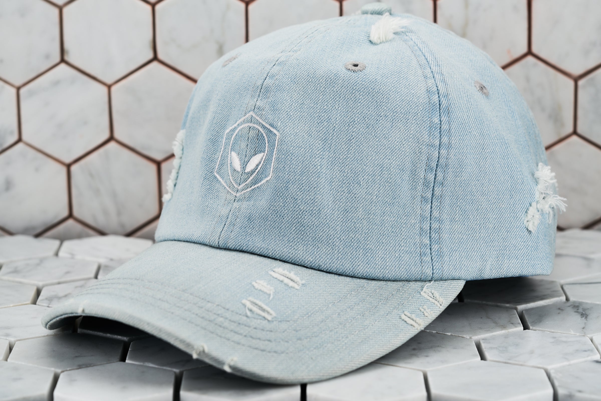 The front view of the distressed denim blue Dear Martian hat, which has a white embroidered hexagon logo.
