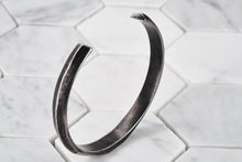 An image of a vintage steel cuff bracelet for men standing up so you see the sharp ends of the bracelet.