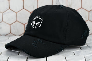 A front product image of the distressed black baseball cap with a white embroidered alien; made by Dear Martian, Brooklyn.