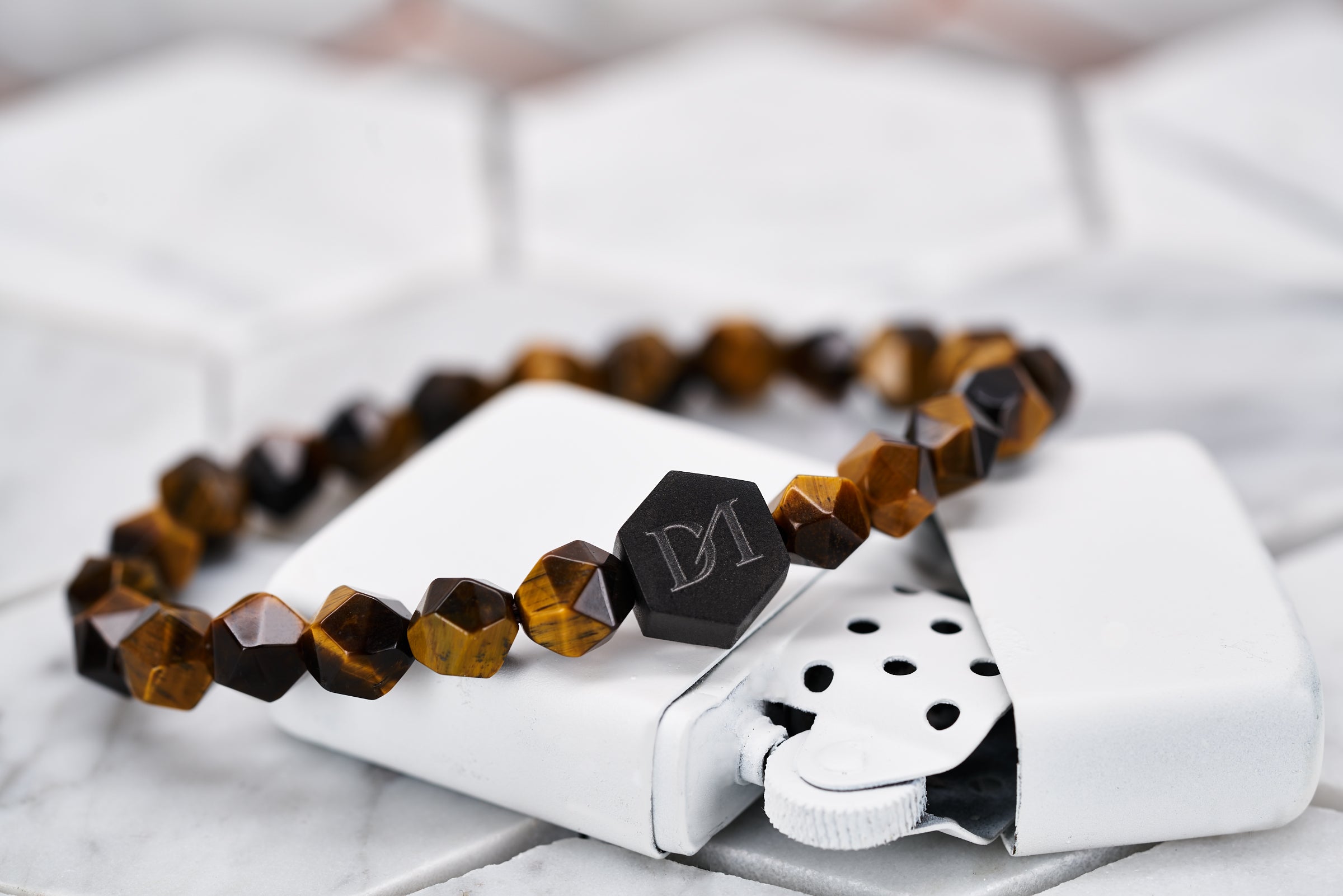 An image of the tiger eye stone bead bracelet by Dear Martian sitting on top of a white zippo lighter.
