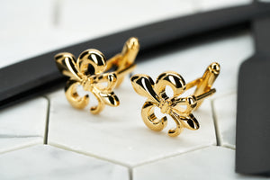 An image of a pair of cufflinks by Dear Martian. They are gold flower of life suit accessories shown against a white hexagonal background. 