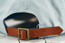 A detailed image of the adjustable brown leather strap displayed on the washed denim cap by Dear Martian, Brooklyn.