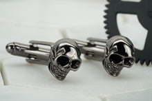 A photo of a pair of Dear Martian gunmetal skull cufflinks.  These  men's cufflinks feature enameled black eyes.