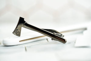 An image showing the back of the Kloven gun metal axe tie clip. The back shows an etched DM signature logo.