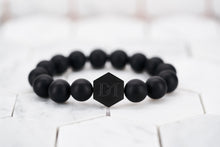 A product image of the men's matte black bead bracelet by Dear Martian with a signature matte black hexagon logo bead.