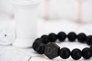 A side view image of the Black Panther matte black obisidian stone bead bracelet by Dear Martian with a hexagon logo bead.