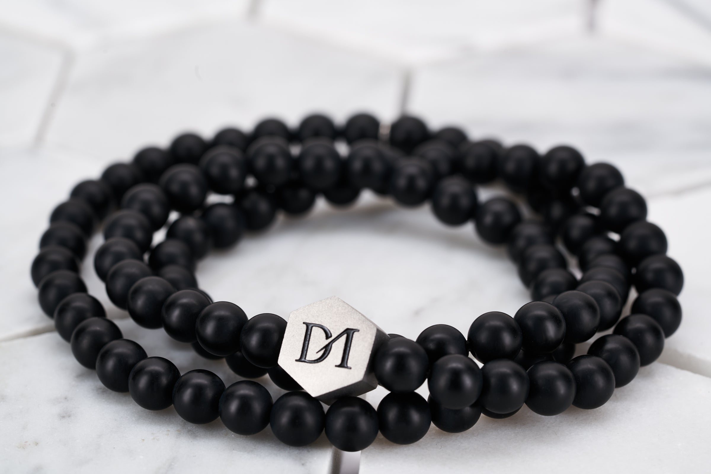 An image of a wrap bracelet made by Dear Martian Brooklyn constructed with matte black obsidian stones that can wrap around the wrist multiple times.