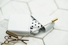 The front image of a gold comb and scissors lapel pin for mens suit jackets, made by Dear Martian.