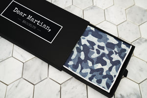 An image of the blue camouflage patterned pocket square inside our Dear Martian, Brooklyn black pull out style box. 