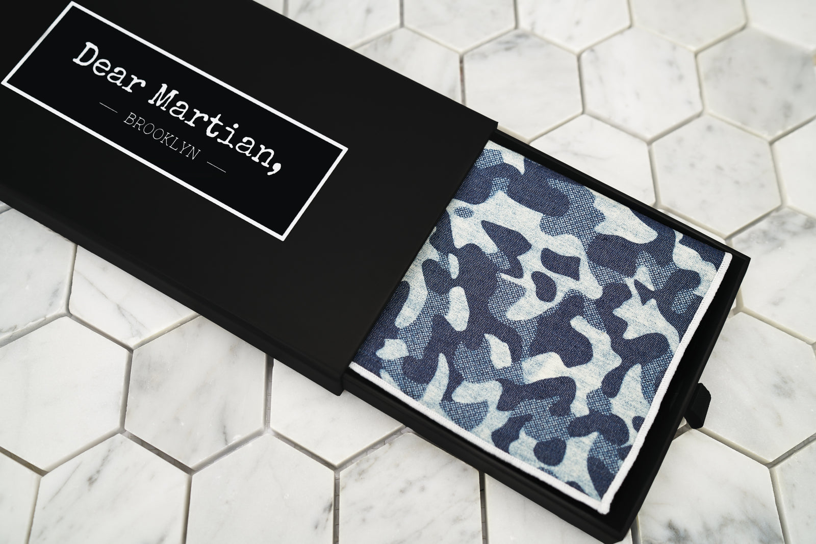 An image of the blue camouflage patterned pocket square inside our Dear Martian, Brooklyn black pull out style box. 