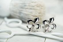 An image of a set of silver cufflinks, which feature a fleur de lis design created by Dear Martian, Brooklyn.