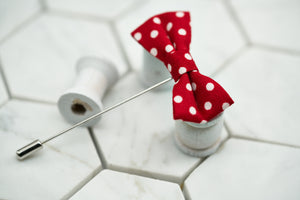 An image of a mini bowtie lapel pin featuring a red and white dotted pattern. This suit accessory is made by Dear Martian, Brooklyn.
