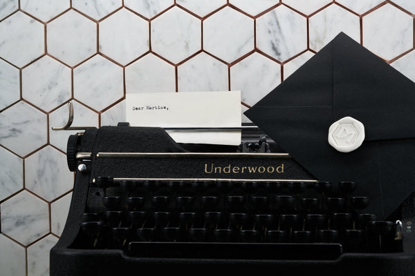 This image signified the add on gift option & depicts a vintage typewriter with a letter with Dear Martian, lastly it shows a wax seal with a hexagonal DM logo on a black envelope.