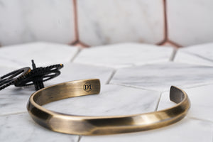 An image of the Dear Martian antique brass cuff bracelet, which shows the DM engraving.