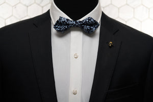 A mannequin accessorized with the Vie gold skull lapel pin and navy floral bow tie by Dear Martian, Brooklyn.