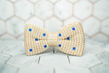 An image of the front of the creme colored, Dear Martian bow tie featuring blue polka dots.