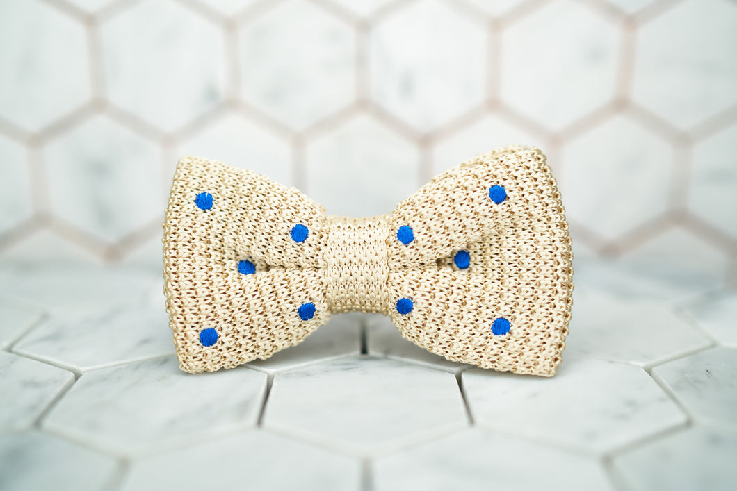 An image of the front of the creme colored, Dear Martian bow tie featuring blue polka dots.