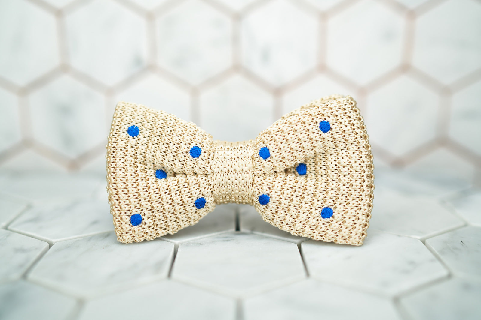 An image of the front of the creme colored, Dear Martian bow tie featuring blue polka dots.