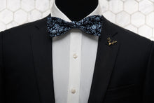 Worn with a black suit and white button down is the Liberty cotton floral bow tie paired with a gold deer lapel pin.