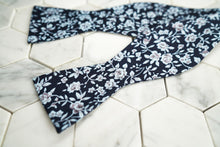 An image of the Dear Martian exclusive Liberty navy floral patterned bow tie; shown across a hexagon background.