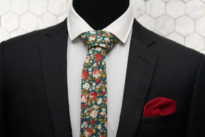 The green floral slim tie from Dear Martian, is paired with a red silk knit pocket square; and displayed on a suited mannequin.