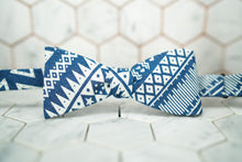 A front view image of the Dear Martian blue denim aztec bow tie tied up against a white hexagonal background.