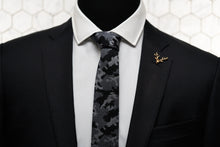 An image of the Dear Martian storm grey tie is shown on a mannequin dressed in a black suit with our antique gold stag lapel pin.