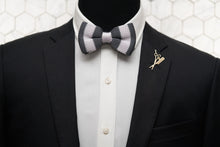 A mannequin wearing a black suit jacket accessorizing with Dear Martian's eseentials; our signature grey and white silk knit bow tie and gold beard and comb lapel pin.
