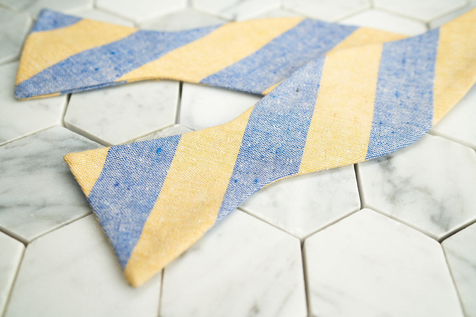 An image of the Dear Martian yellow and blue striped linen bow tie; lying flat and untied.