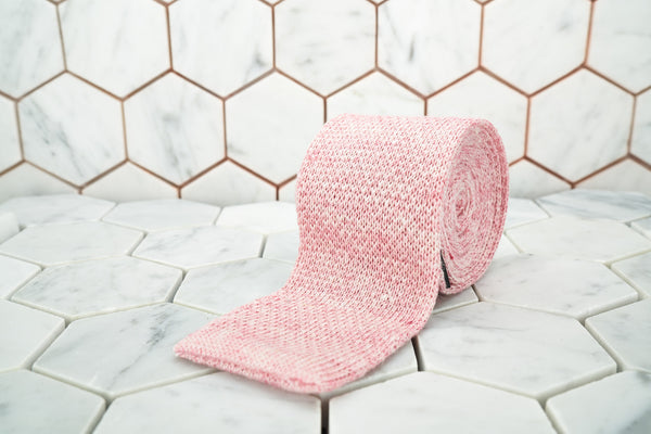 Dear Martian exclusive pink linen knitted tie rolled against a hexagonal background.