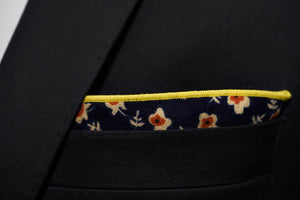 An image of a men's floral pocket square by Dear Martian, is shown folded inside a black suit jacket pocket.