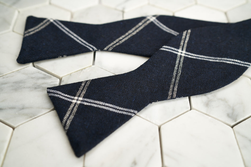 An aerial image of a navy argyle linen blended bow tie by Dear Martian, Brooklyn.