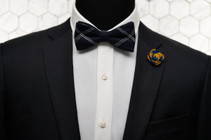 A mannequin wearing the epitome of modern men's fashion; a navy striped bow tie and a yellow and navy flower lapel pin.