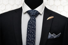 A mannequin is wearing Dear Martian's men accessories, which features our navy paisley tie, the Pratt navy pocket square, and Veder gold feather lapel pin.