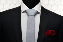 Dear Martian tie with stripes is paired with our men's red knitted pocket square and displayed on a black suit jacket.