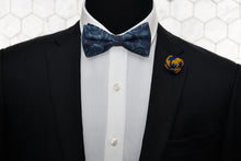 A mannequin dressed in Dear Martian men's accessories; a blue denim floral patterned bow tie and a navy yellow flower lapel pin.
