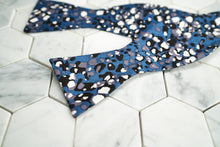 An image of the Crooke indigo spotted bow tie lying on a hexagonal background.
