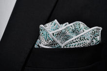 An image of Dear Martian, Brooklyn's Whitman cotton white pocket square featuring an array of leaves is shown folded in a pocket.