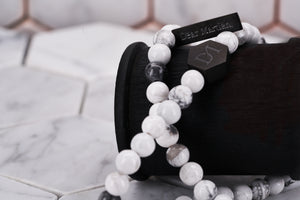 A close up image of the Dear Martian wrap jewelry bracelet showing the Dear Martian engraved tag and hexagon logo bead. It features 6mm white howlite stone beads.